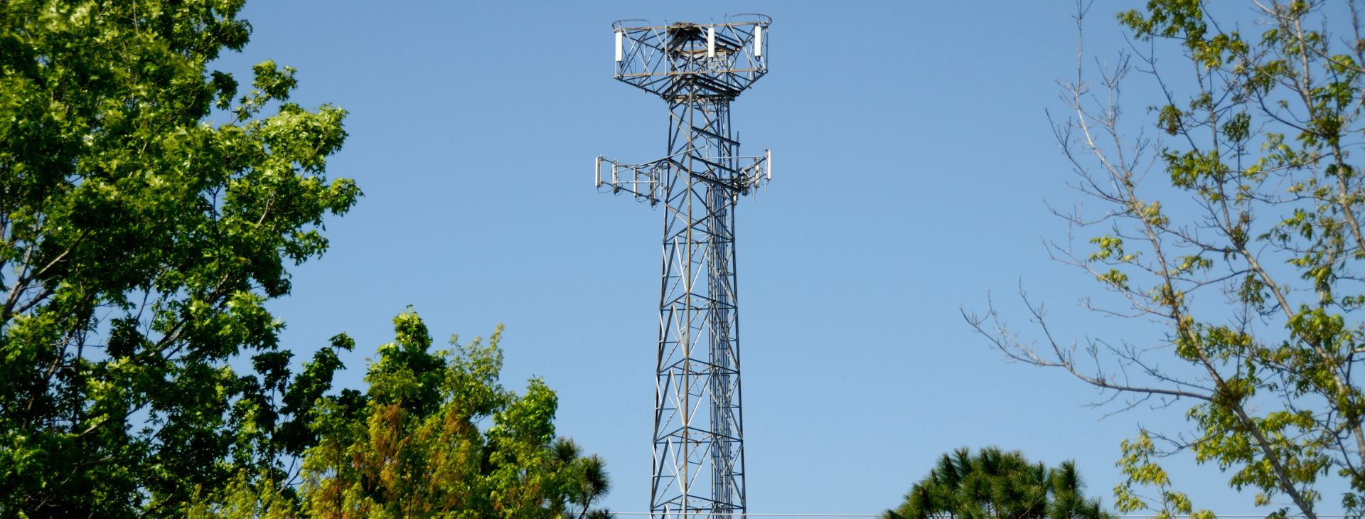 A cell phone tower with a tall metal antenna standing tall against the sky.